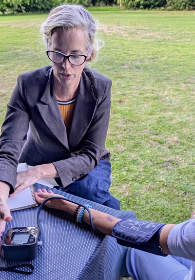 A wellbeing practitioner checking someone's blood pressure at an outdoor community event